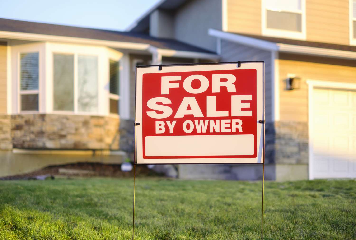 A 'For Sale by Owner' sign in front of a picturesque home, signifying the initial step many take to sell their homes without a realtor.